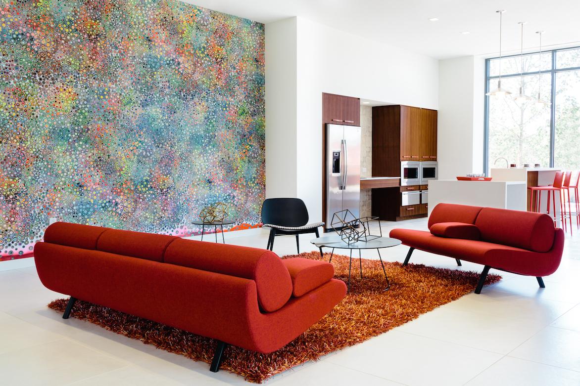 Common seating area with modern style couches, shag rug, kitchenette area with fridge, counters, and two ovens, and a floor to ceiling wall abstract wall mural