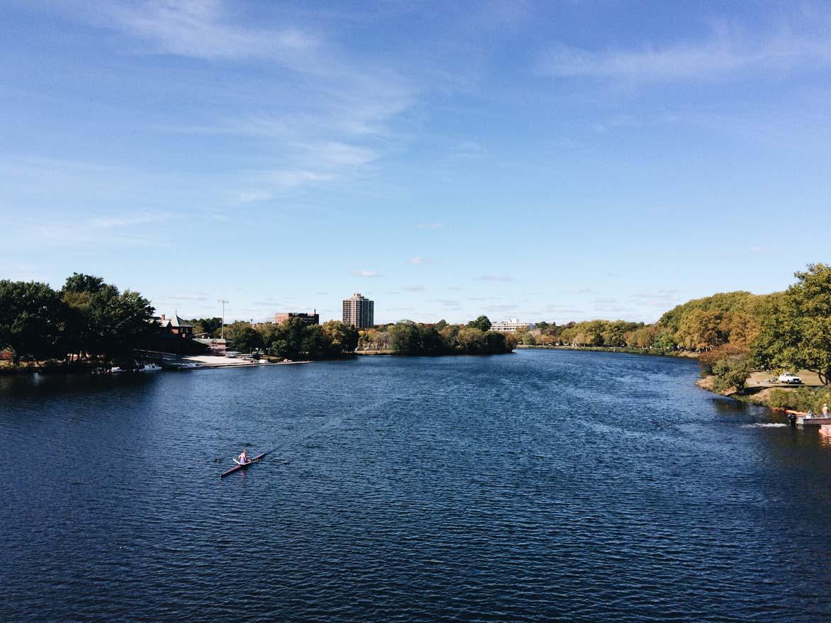Crew rower training on the Charles River during a sunny day with blue skies
