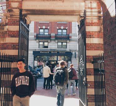 Students walking under Harvard University's freshman gates made of alternating rows of brick and white stone 